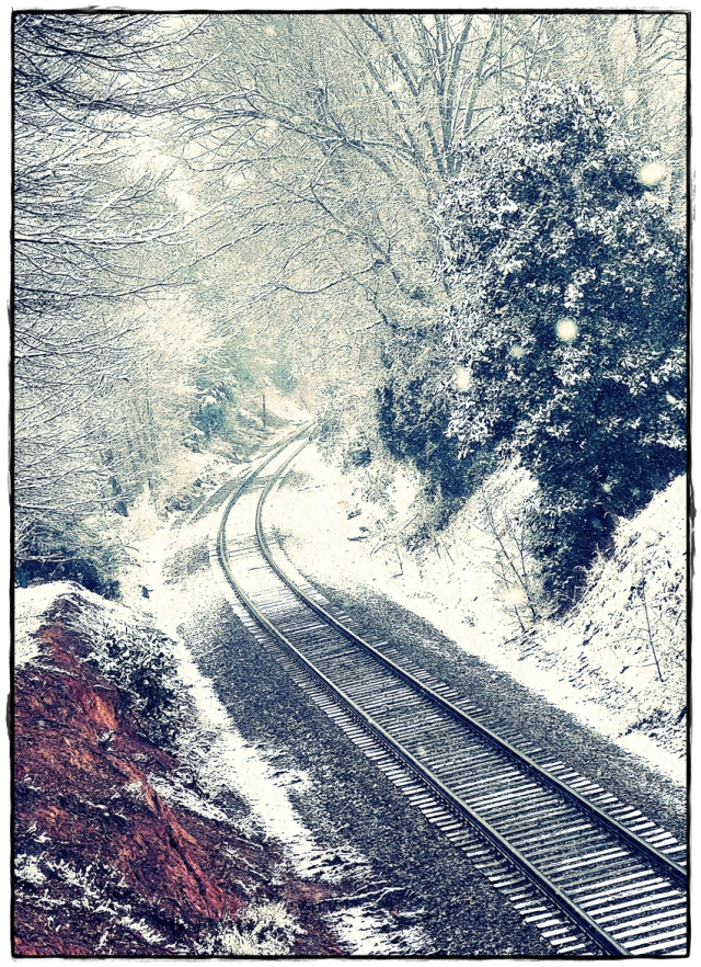 Train tracks disappearing into a wintery wonderland.